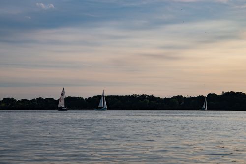 Free Serene view of a lake with sailboats and a beautiful sunset sky. Ideal for travel and nature themes. Stock Photo