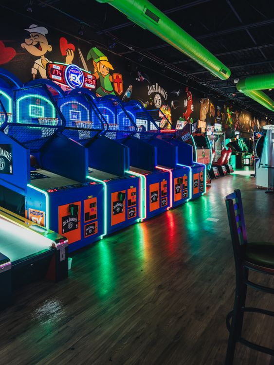 Salón recreativo arcade con luces de neón, años 80