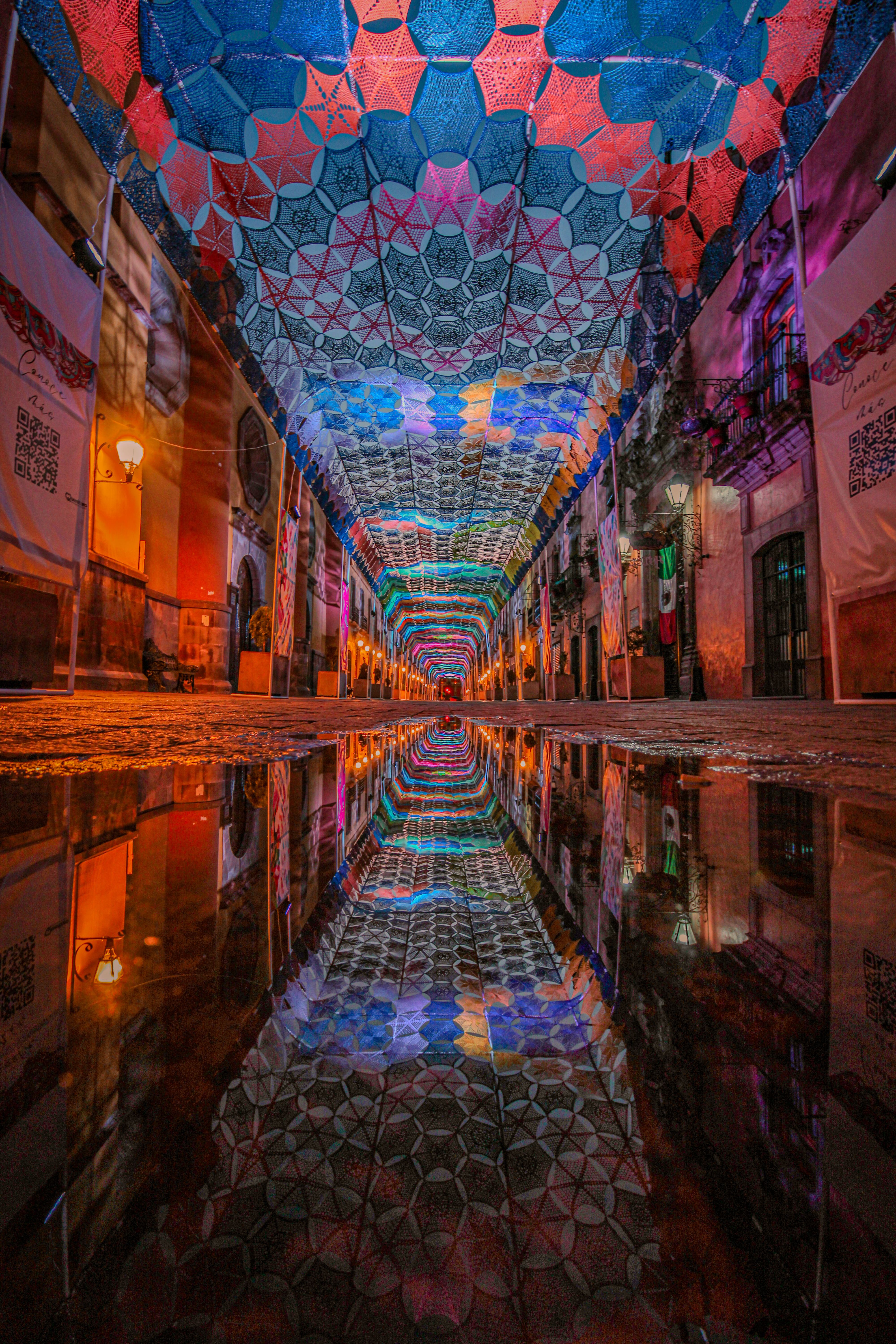 Colorful illuminated street with artistic ceiling reflection at night. Captivating urban scene.