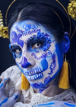Vibrant face paint depicting Dia de los Muertos theme with blue designs and decorative details.