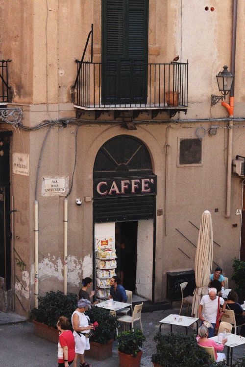 Free A bustling outdoor Italian cafe with patrons enjoying a sunny day in a quaint neighborhood. Stock Photo