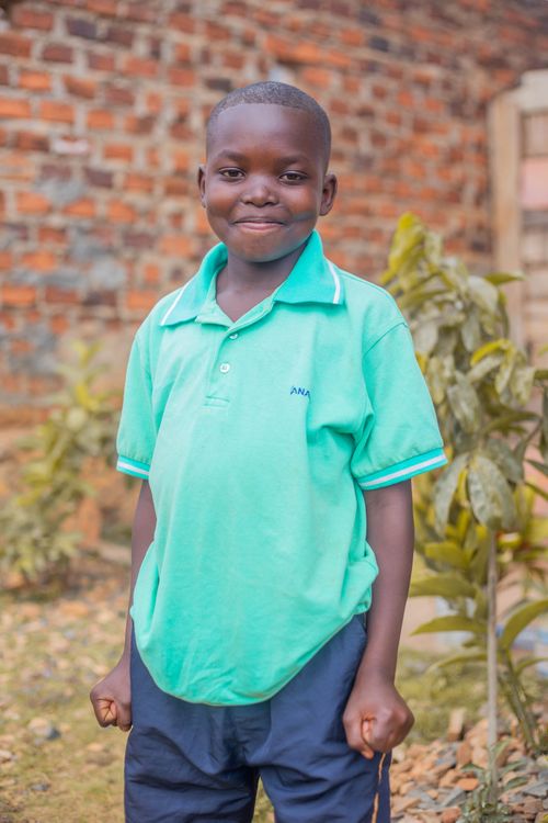 Free A cheerful young boy stands outdoors wearing a green polo shirt, smiling warmly. Stock Photo