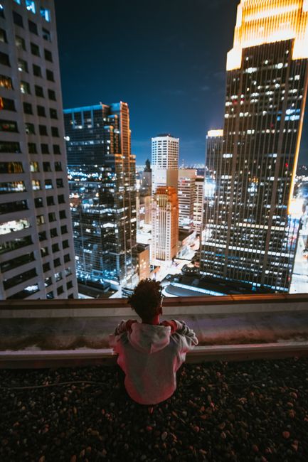 Person overlooking nighttime city skyline from a rooftop in downtown Minneapolis.