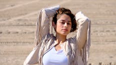 在阳光明媚的户外，一位时尚的女人穿着刘海夹克摆姿势