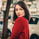 一位时尚女士穿着红色毛衣，在城市环境中自信地摆出姿势