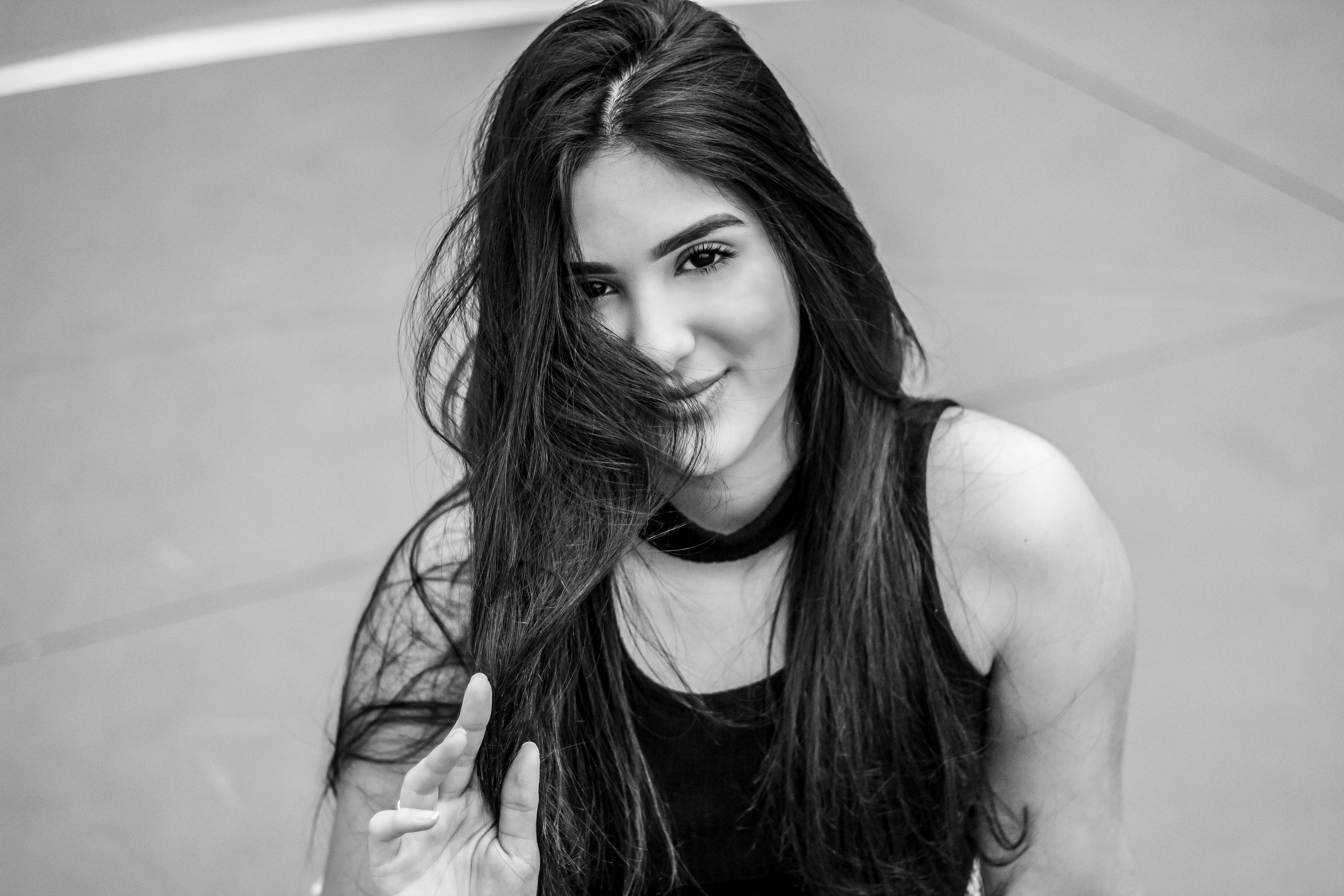 一张黑白肖像，拍的是户外一位微笑的长发女子