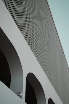 低角度拍摄的现代建筑立面，拱门与网格图案展现极简主义风格