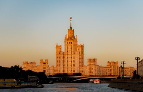 Free A stunning view of a tall, historic building beside the Moskva River, illuminated by warm sunset colors. Stock Photo