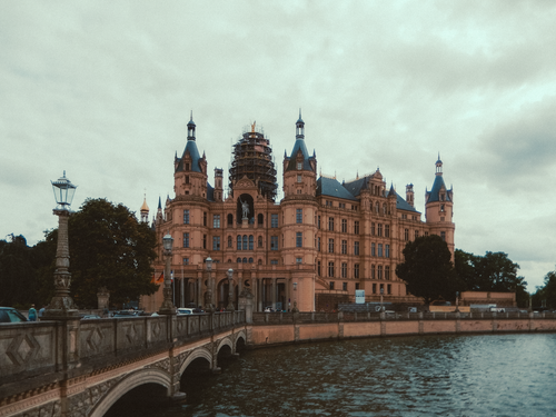Free Schwerin Castle with surrounding bridge under cloudy skies. Stock Photo