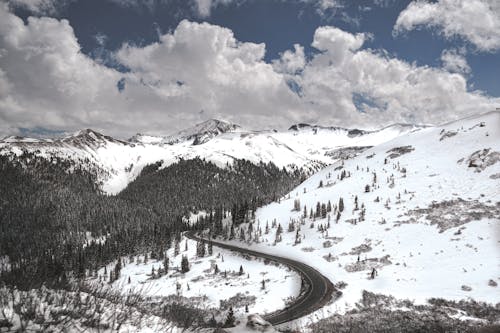 Free Aerial Photograph Of A Road Surrounded By Snow Covered Mountains Stock Photo