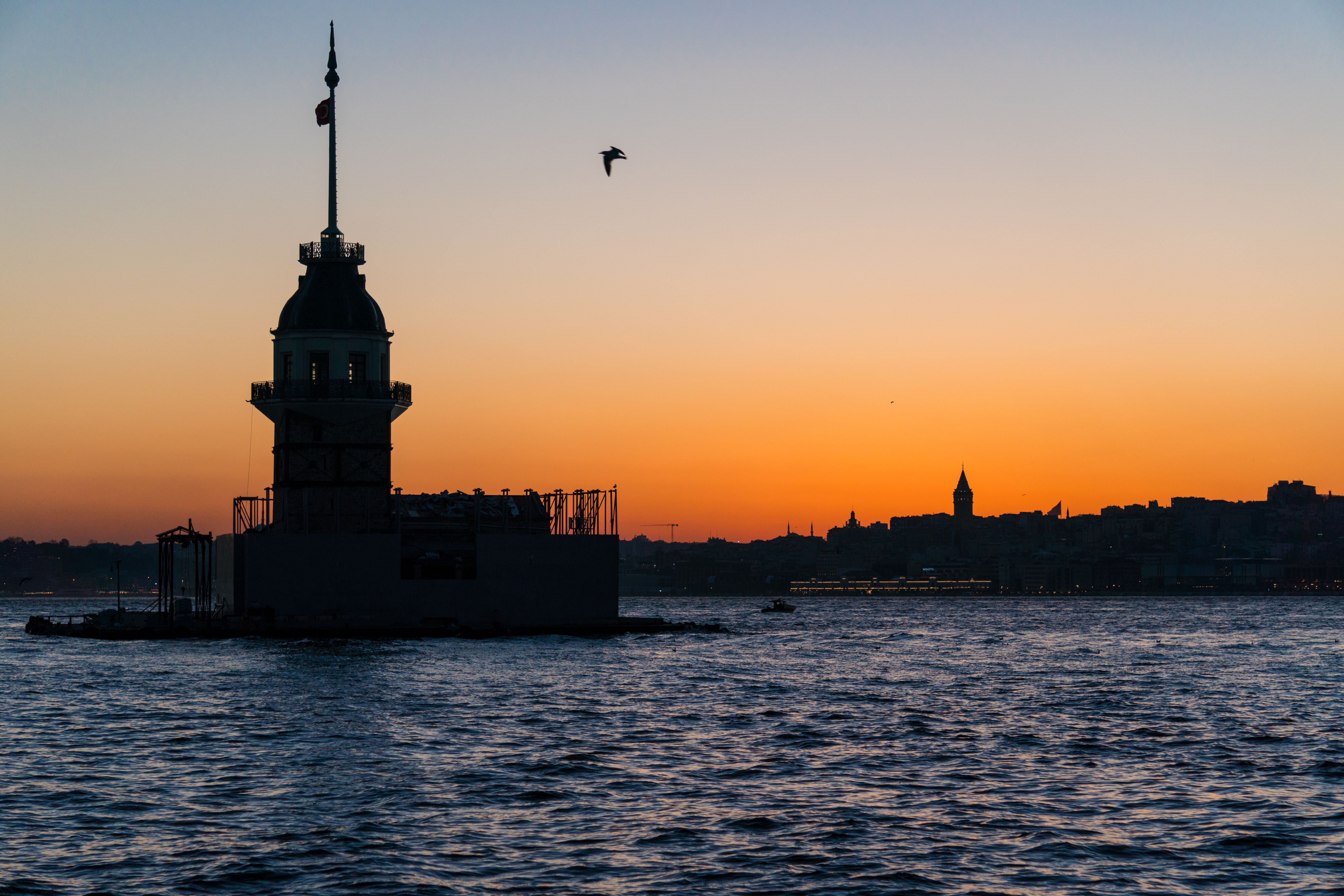 Stunning view of Kız Kulesi and Galata Tower silhouetted against a vibrant Istanbul sunset.