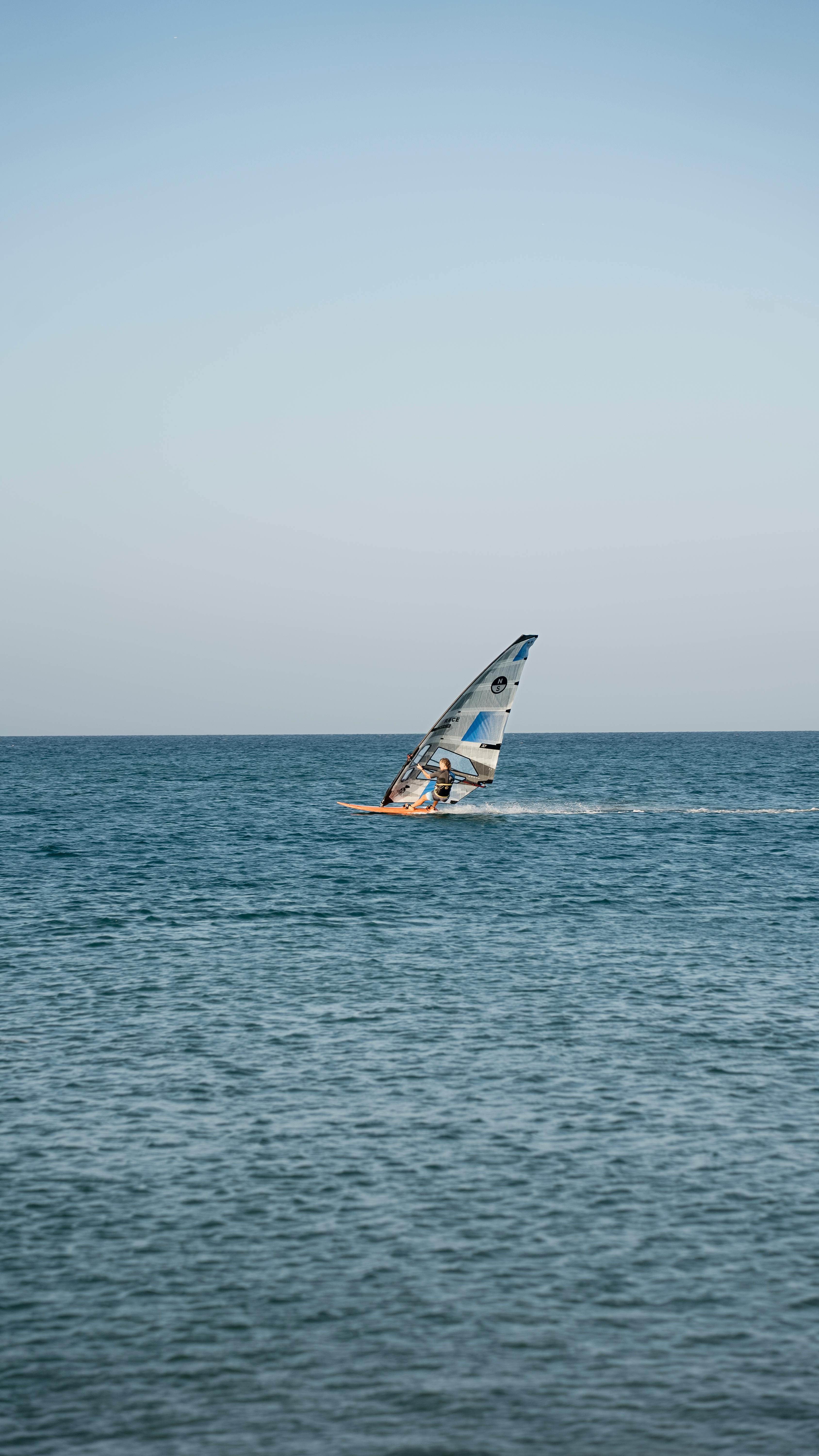 A lone windsurfer rides the waves on a sunny day in Gökçeada, Turkey.