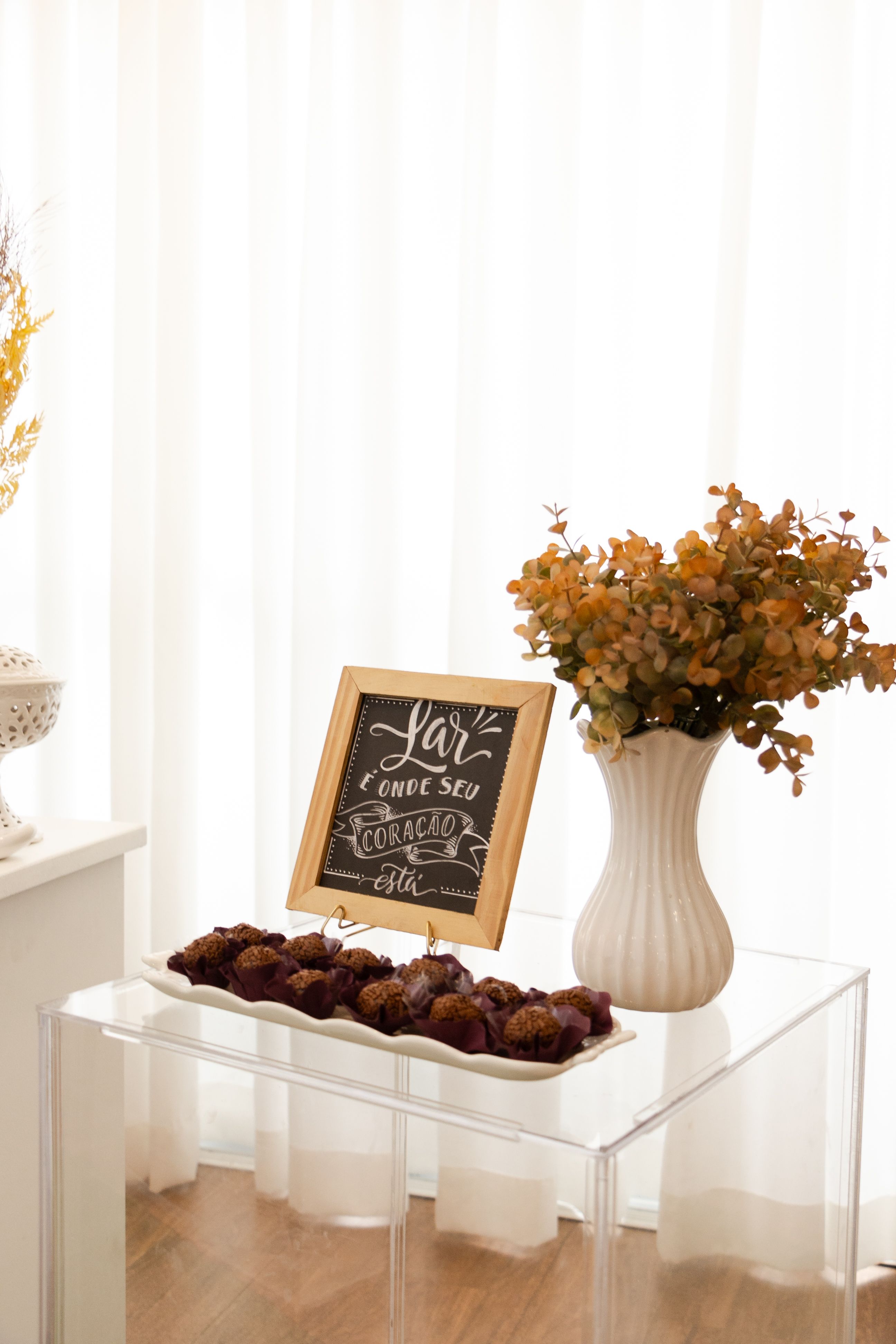 Warm indoor setup with floral vase, framed sign, and treats in São Paulo.
