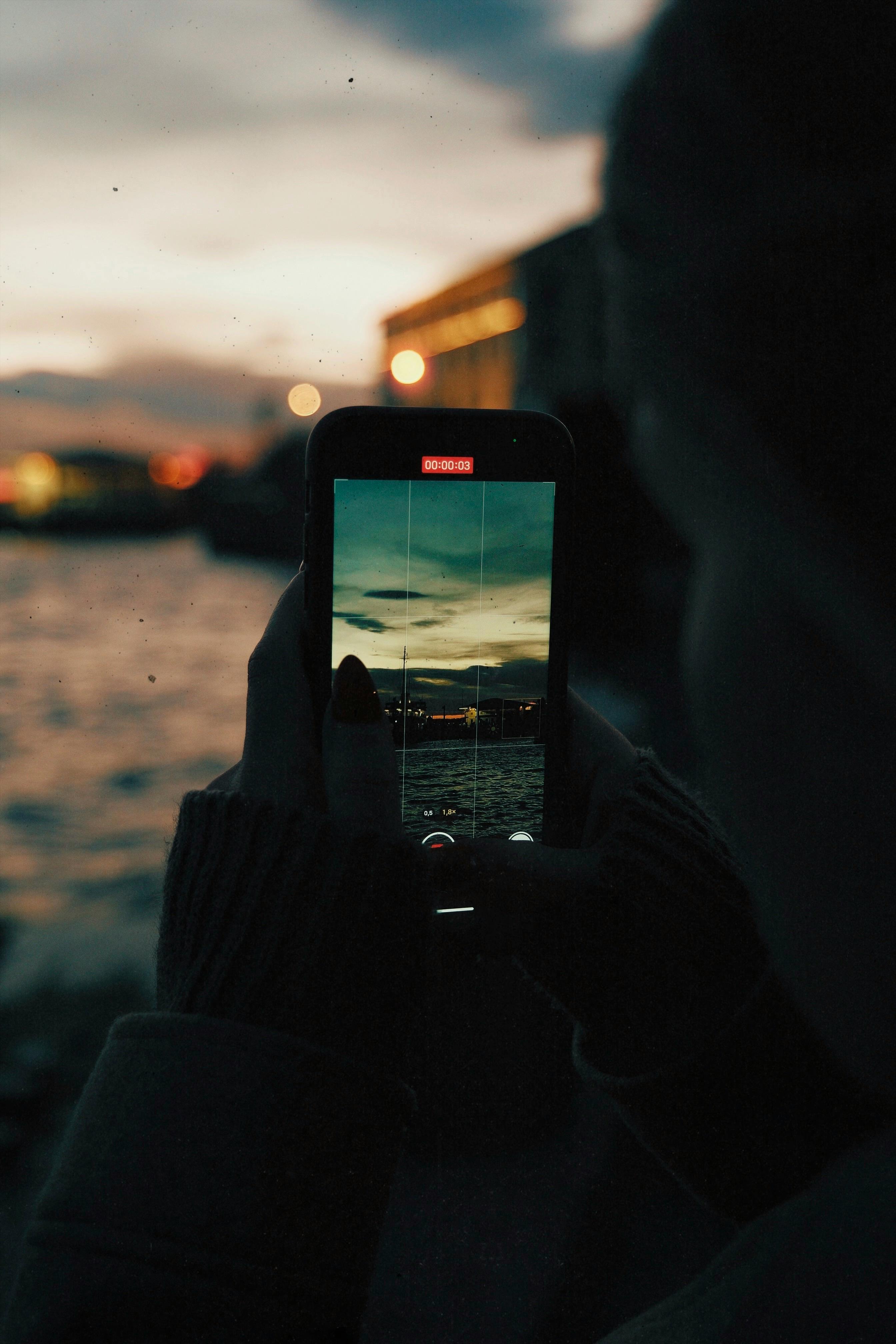 Silhouette capturing a sunset over water using a smartphone camera.