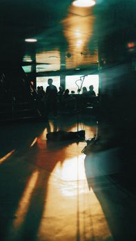 Sunlit interior with people silhouettes and microphone stand, creating a moody atmosphere.