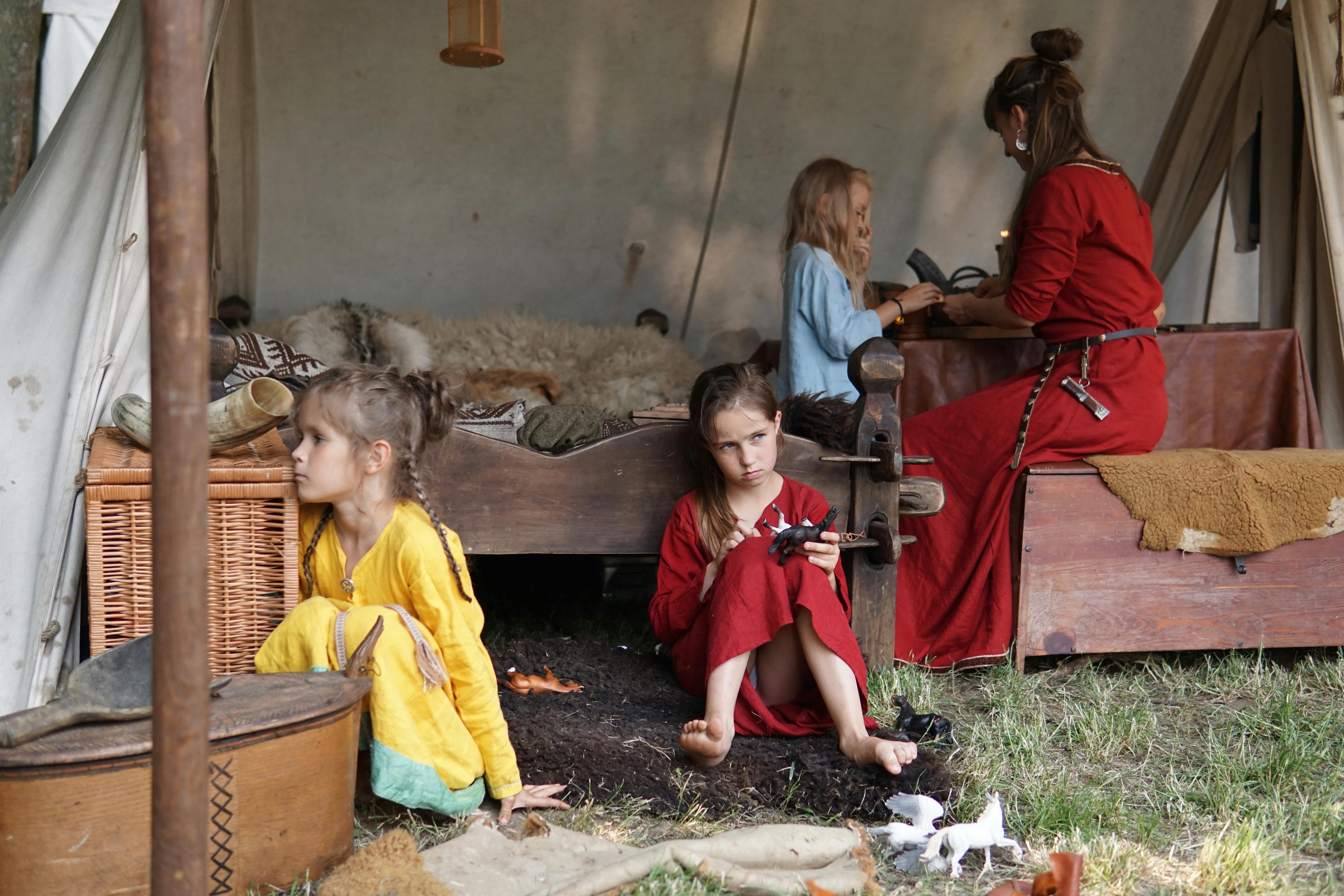 Family scene depicting children and adult in historical tent setting with vintage garments.