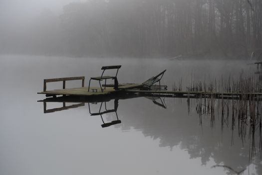 Calm pier on a foggy lake with tranquil reflections highlighting serene nature.