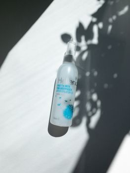 A bottle displayed against a leaf-shadowed background in direct sunlight, evoking a natural theme.