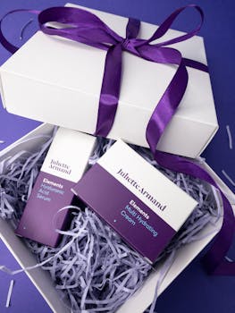 White gift box with purple skincare products and ribbon, perfect for a luxurious present.