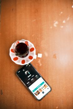 Top view of a smartphone with a tea glass on a wooden table.