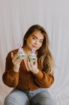 Smiling woman holding decorated cupcakes for a birthday celebration.