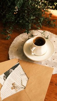 A cup of coffee with vintage letters on a wooden table creates a warm, nostalgic atmosphere.