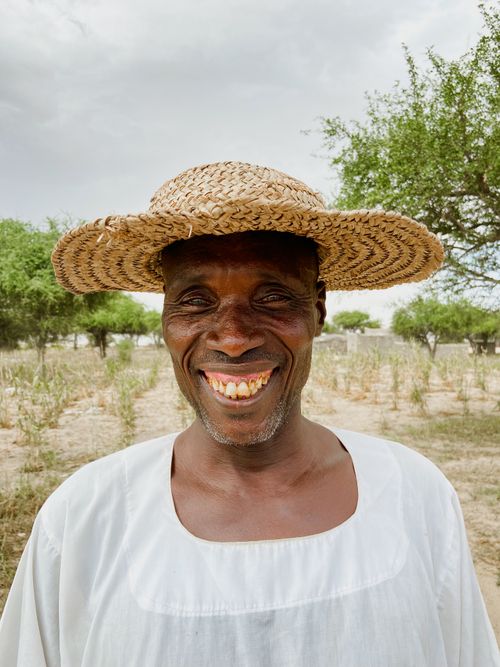 Free A cheerful farmer wearing a straw hat smiles in a rural landscape. Stock Photo