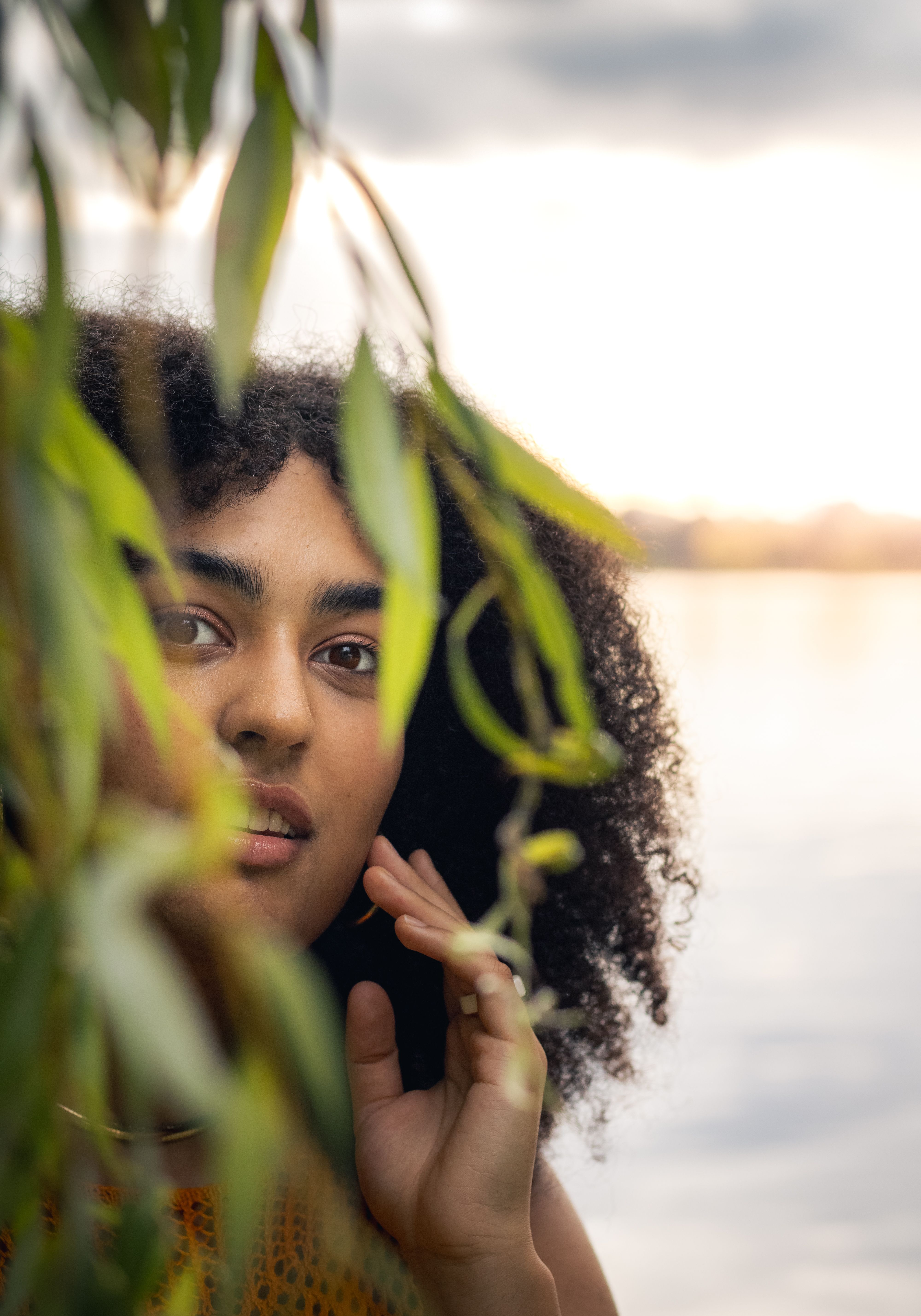 Young Woman Among Greenery by Water at Sunset · Free Stock Photo