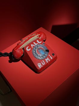 A vintage red rotary phone with the words 'CALL RUMI' in a vibrant display.