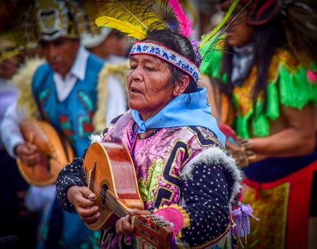 Indigenous Mexican woman performing traditional music in vibrant attire at a cultural event.