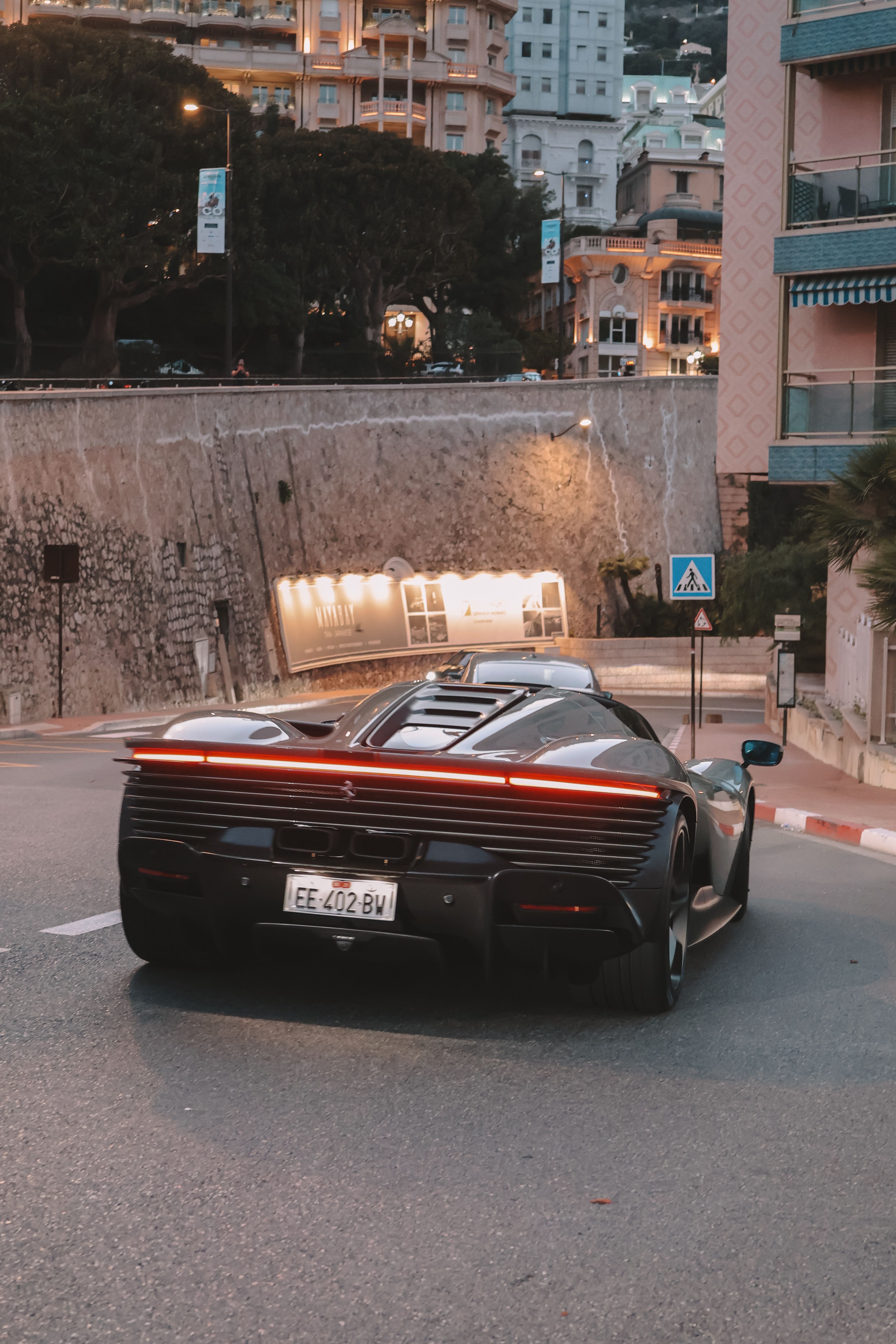 A luxurious black sports car on a city street at dusk in Dubai