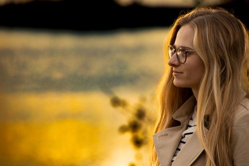 Free A contemplative woman by the river at sunset in autumn. Stock Photo
