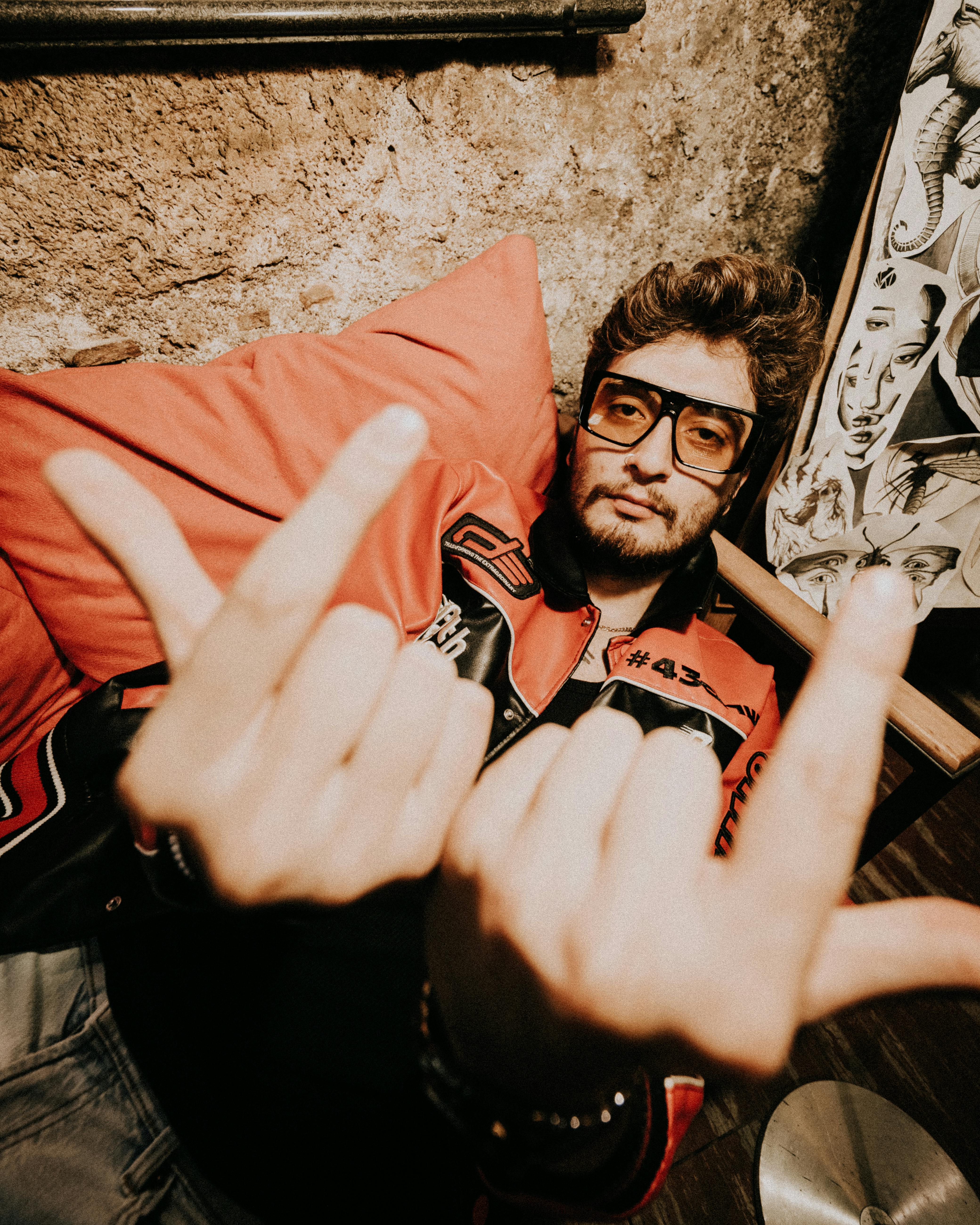 A young man in a trendy jacket relaxing on a couch, displaying an edgy attitude.