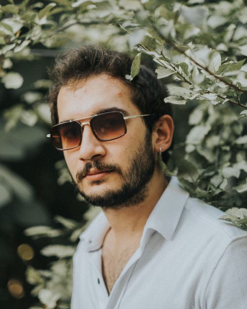 Free Stylish portrait of a man wearing sunglasses surrounded by greenery in Antalya, Türkiye. Stock Photo