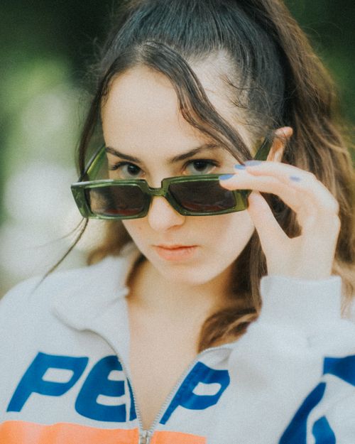 Free A modern young woman adjusts her sunglasses, showcasing a trendy fashion look in Antalya, Türkiye. Stock Photo
