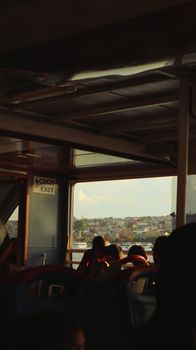 View through ferry window showcasing cityscape and passengers in silhouette.