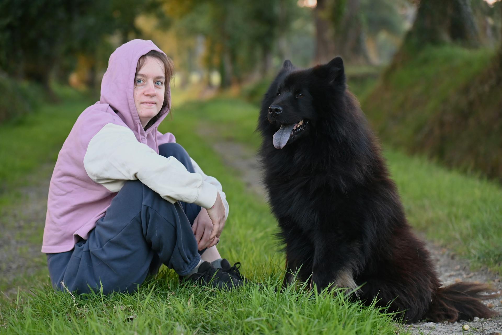 En ung kvinna som slappnar av med en stor svart hund utomhus