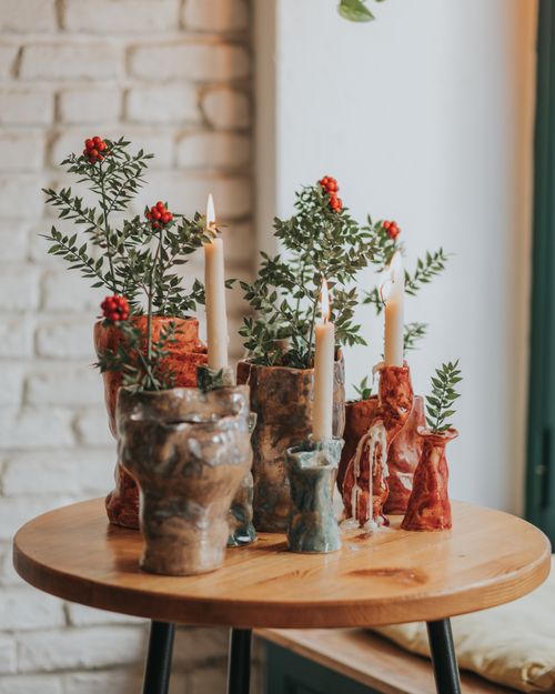 Free Charming ceramic candle holders adorned with greenery on a wooden table. Stock Photo