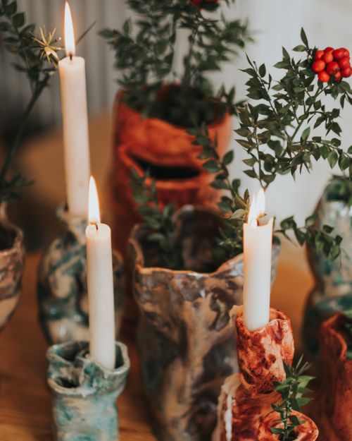 Free Unique ceramic candle holders with candles and greenery on a wooden table. Stock Photo
