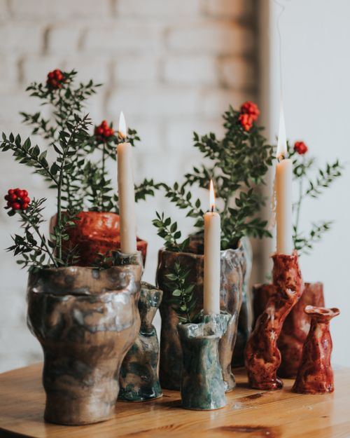 Free Artistic ceramic candle holders with greenery and berries set in a cozy indoor setting. Stock Photo