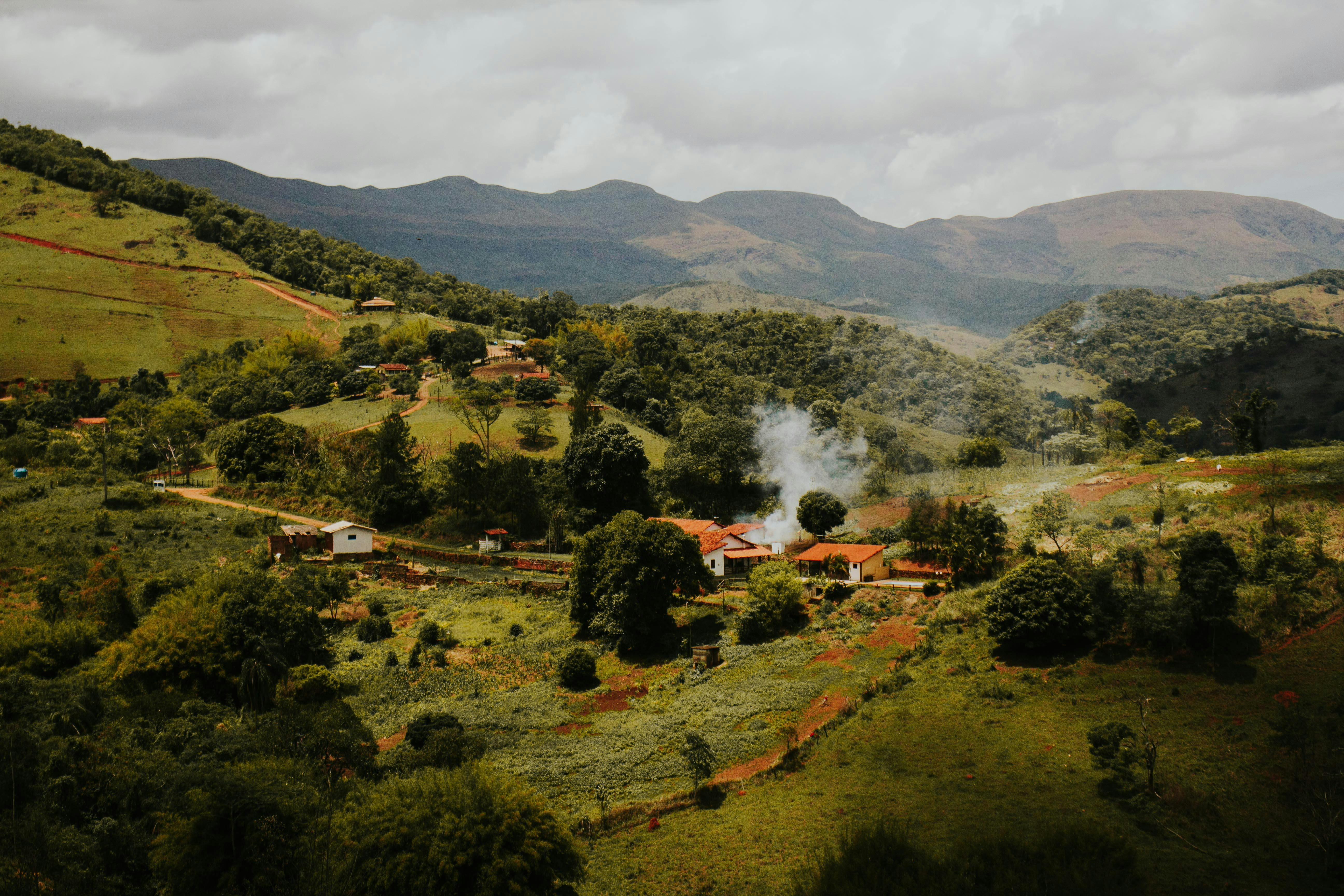 A picturesque rural village nestled amidst green hills and mountains, showcasing serene countryside beauty.