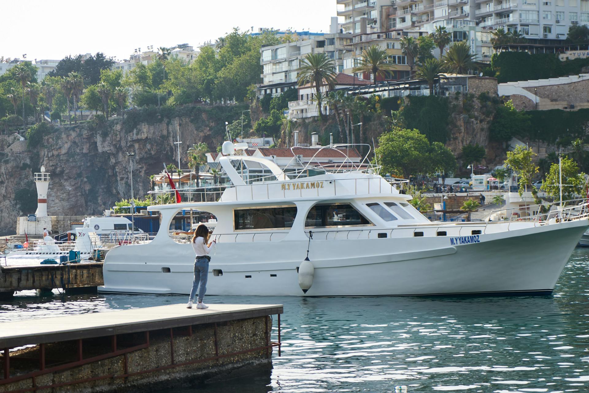 Elegant white yacht docked at a vibrant Mediterranean marina, perfect for summer travel and relaxation.