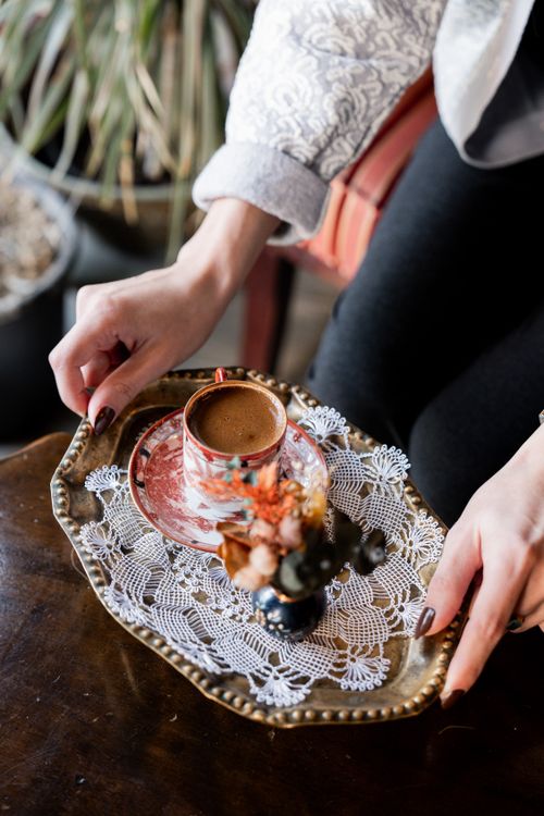 Free A delicate Turkish coffee setup on an ornate tray with lace detail, held by a woman's hands. Stock Photo