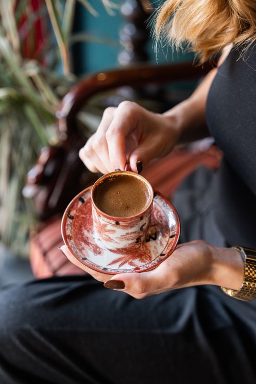 Free Elegant presentation of traditional Turkish coffee in a floral cup held by a woman. Stock Photo