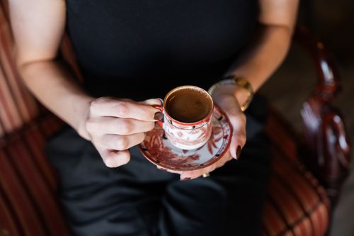 Free A woman holding a traditional Turkish coffee in an ornate cup, highlighting cultural elegance. Stock Photo