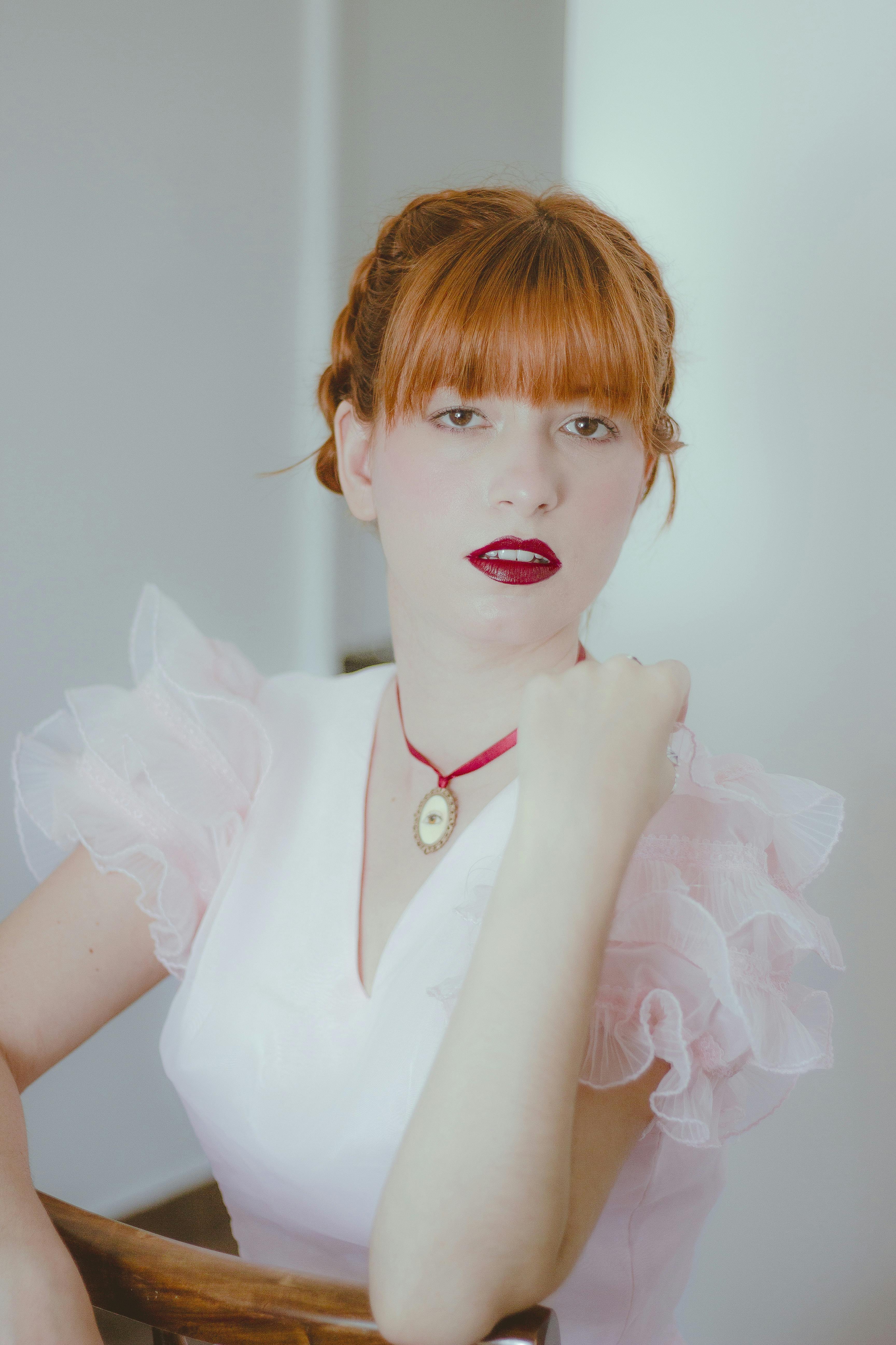 Elegant portrait of a redhead woman with bold red lipstick in a vintage dress. Stylish and artistic mood.