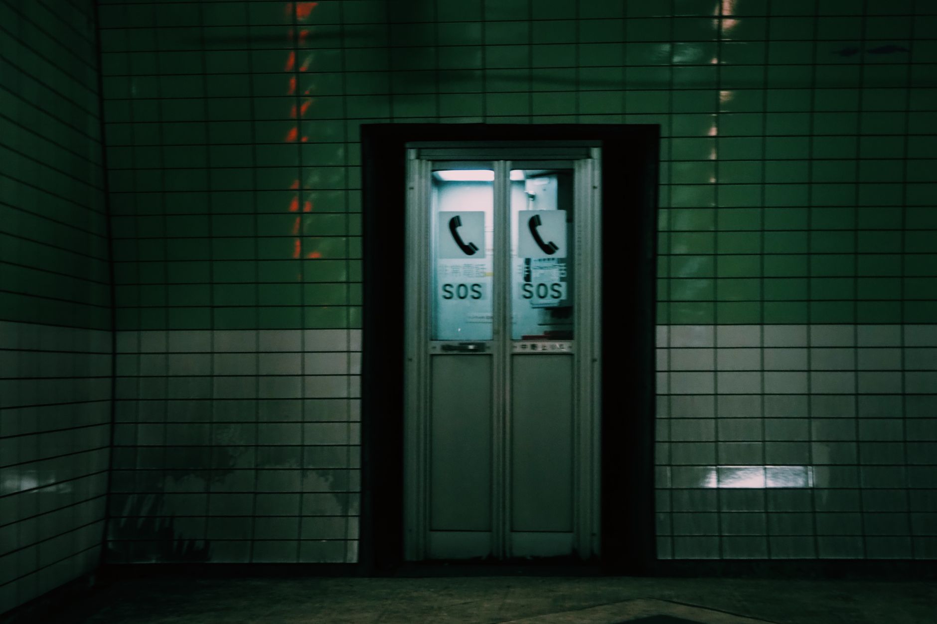 手機導航在國外夜間安全:地圖熱區與警示實戰指南 Moody image of a phone booth labeled SOS in a dimly lit Tokyo subway station