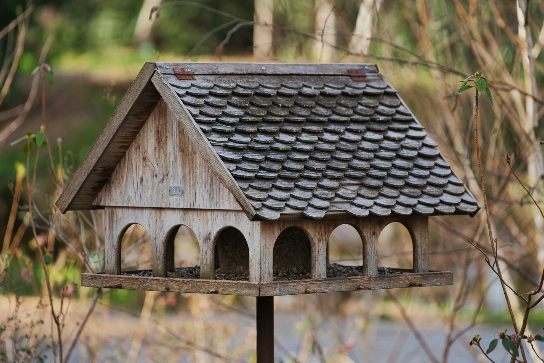 A rustic birdhouse with tiled roof amidst nature, perfect for wildlife enthusiasts.