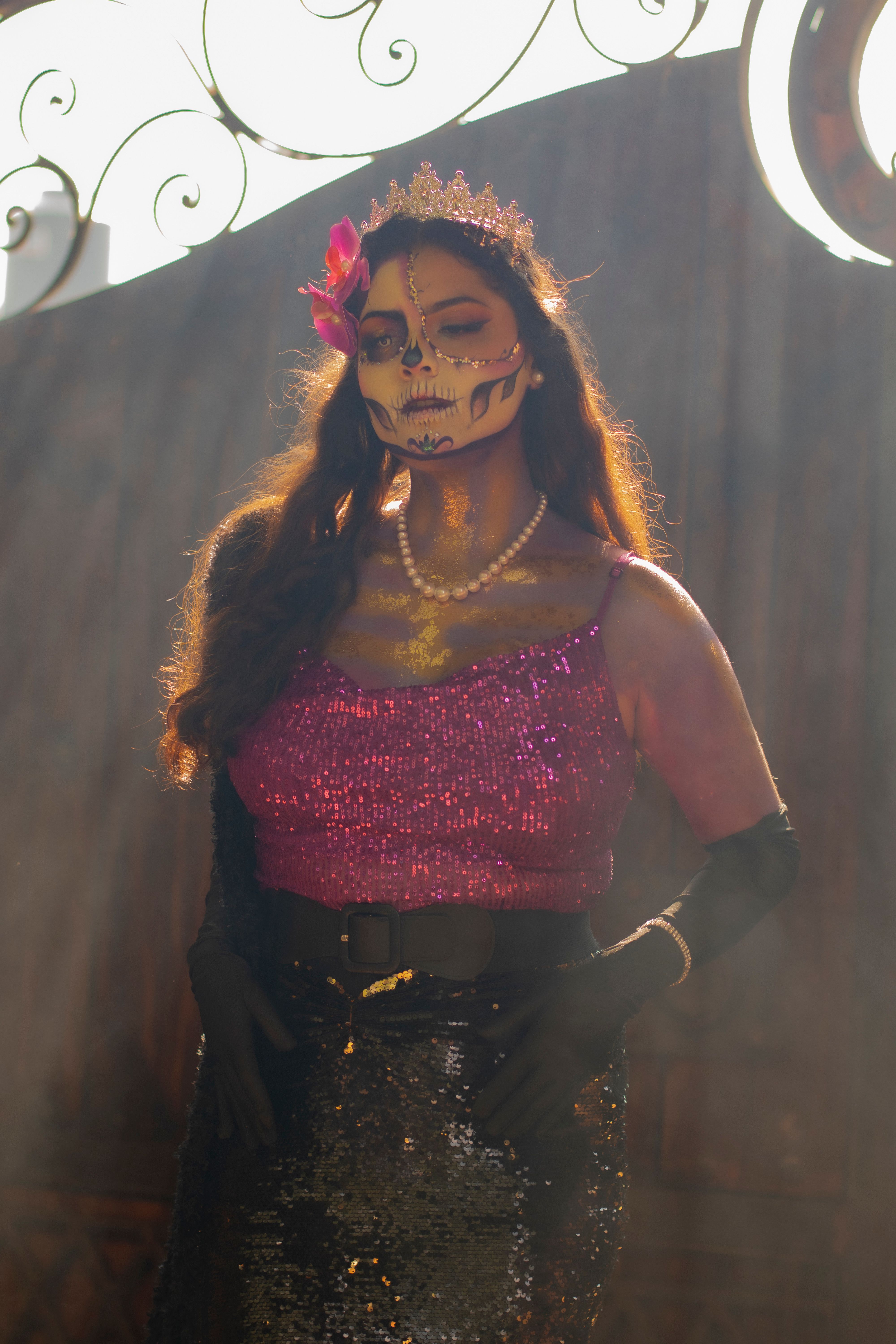 A woman in colorful Day of the Dead makeup and attire stands confidently.