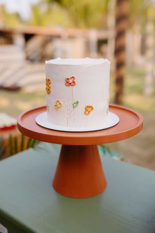 Free A beautifully decorated floral cake on a unique orange stand, set in an outdoor ambiance. Stock Photo